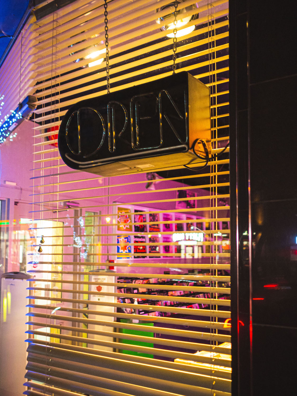 Illuminated window of a record shop with an open sign that is off.